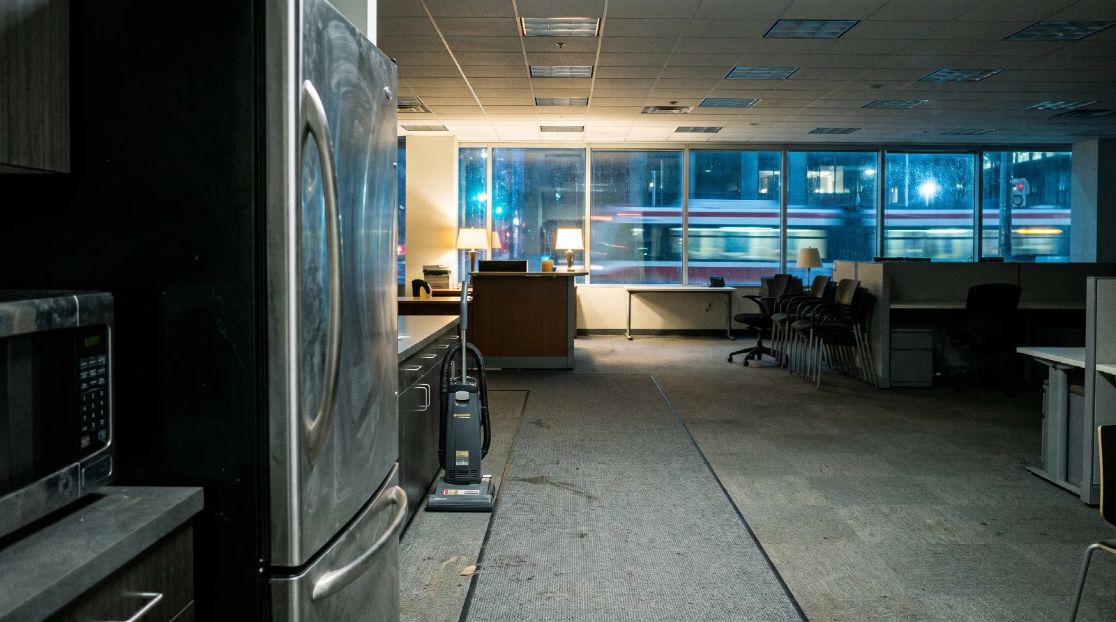 Empty Toronto office kitchenette at night with a vacuum parked on the carpet lane, ready for after-hours office cleaning